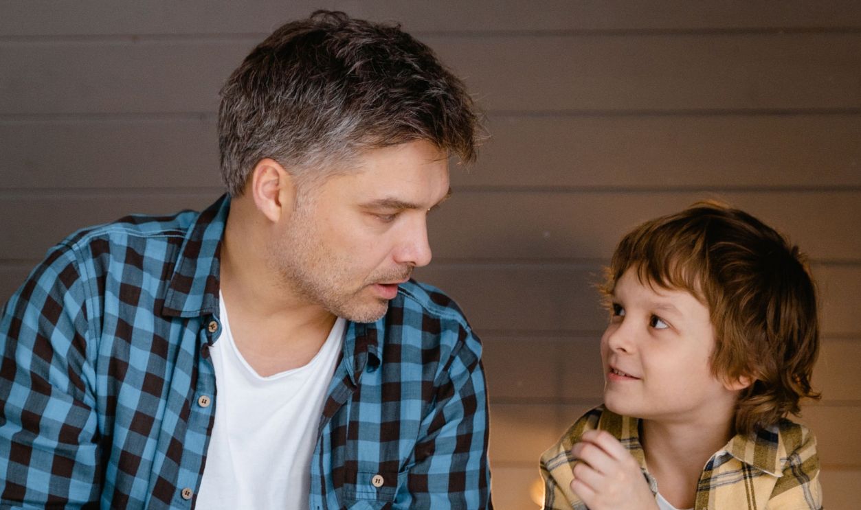 A father and son share a bonding moment reading together indoors, fostering family