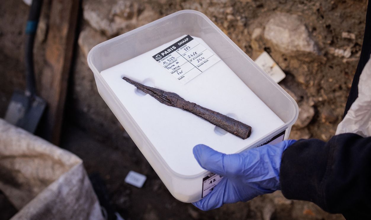 Getty Images - 2296126351 - Elodie Perugini, archeologist for the city of Paris, holds an iron spearhead during excavations at an archaeological site under the Hotel-Dieu hospital on the Ile de la Cite in central Paris, on September 23, 2026. A Gallo-Roman era wall of Lutetia was recently discovered at the site.