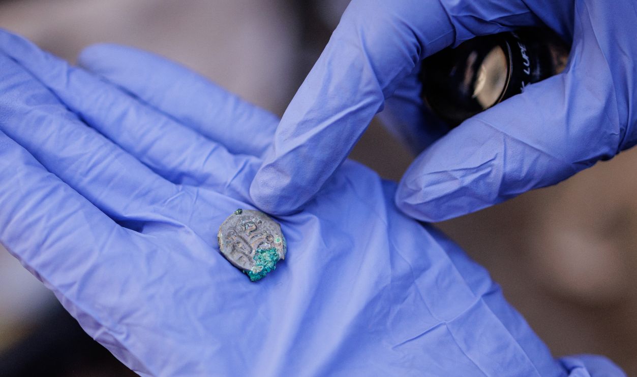 Getty Images - 2296126544 - Elodie Perugini, archeologist for the city of Paris, holds a Gallic coin during excavations at an archaeological site under the Hotel-Dieu hospital on the Ile de la Cite in central Paris, on September 23, 2026. A Gallo-Roman era wall of Lutetia was recently discovered at the site.