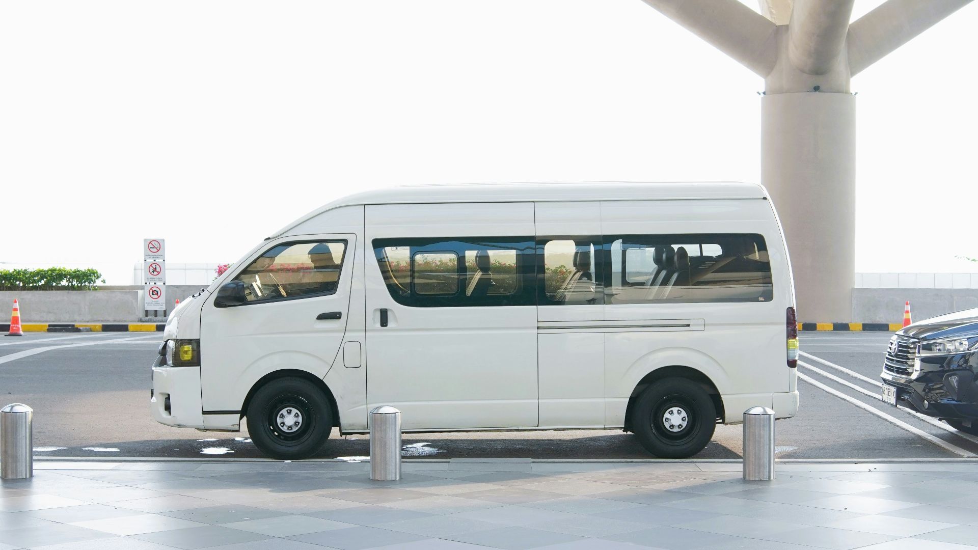 A white van parked at an airport terminal drop-off zone