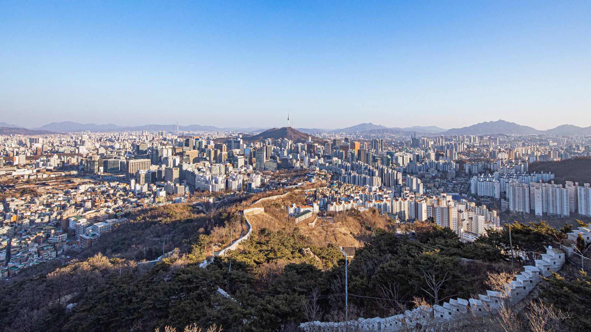 The Seoul City Wall, surrounding the Downtown Seoul at the center of the photo, is lying between Cheongunhyoja-dong on the left, and Muak-dong on the right