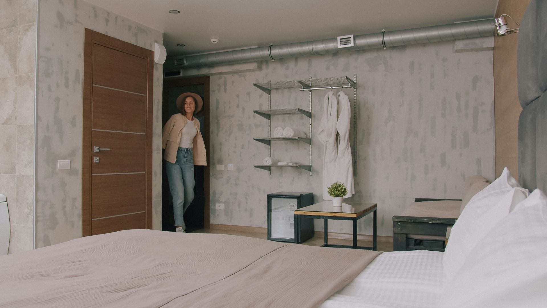 A woman in a hat and jacket entering a modern hotel room