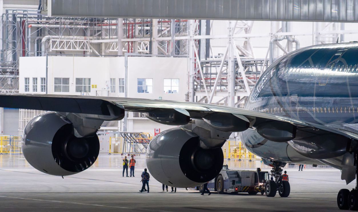A commercial airplane undergoes maintenance in a spacious hangar, highlighting engineering excellence.