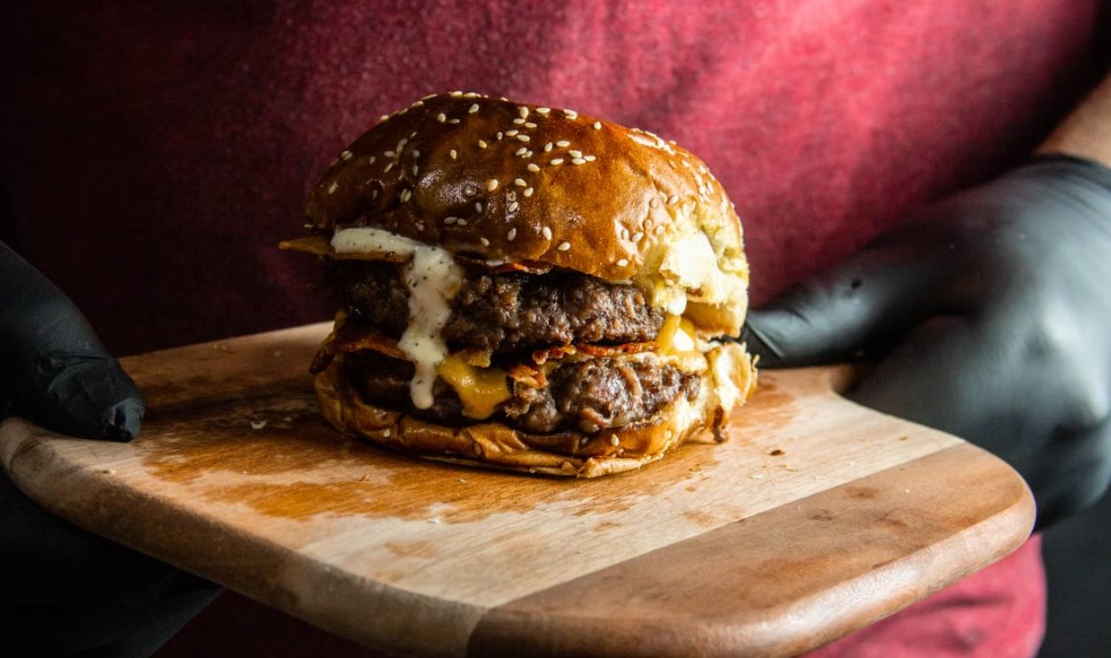 Mouth-watering double cheeseburger with bacon on a wooden board, perfect for food lovers