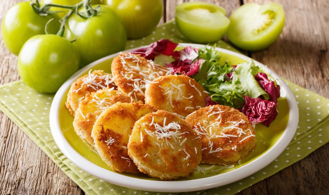American food: fried green tomatoes with fresh salad close-up on a plate and ingredients on a table. horizontal
