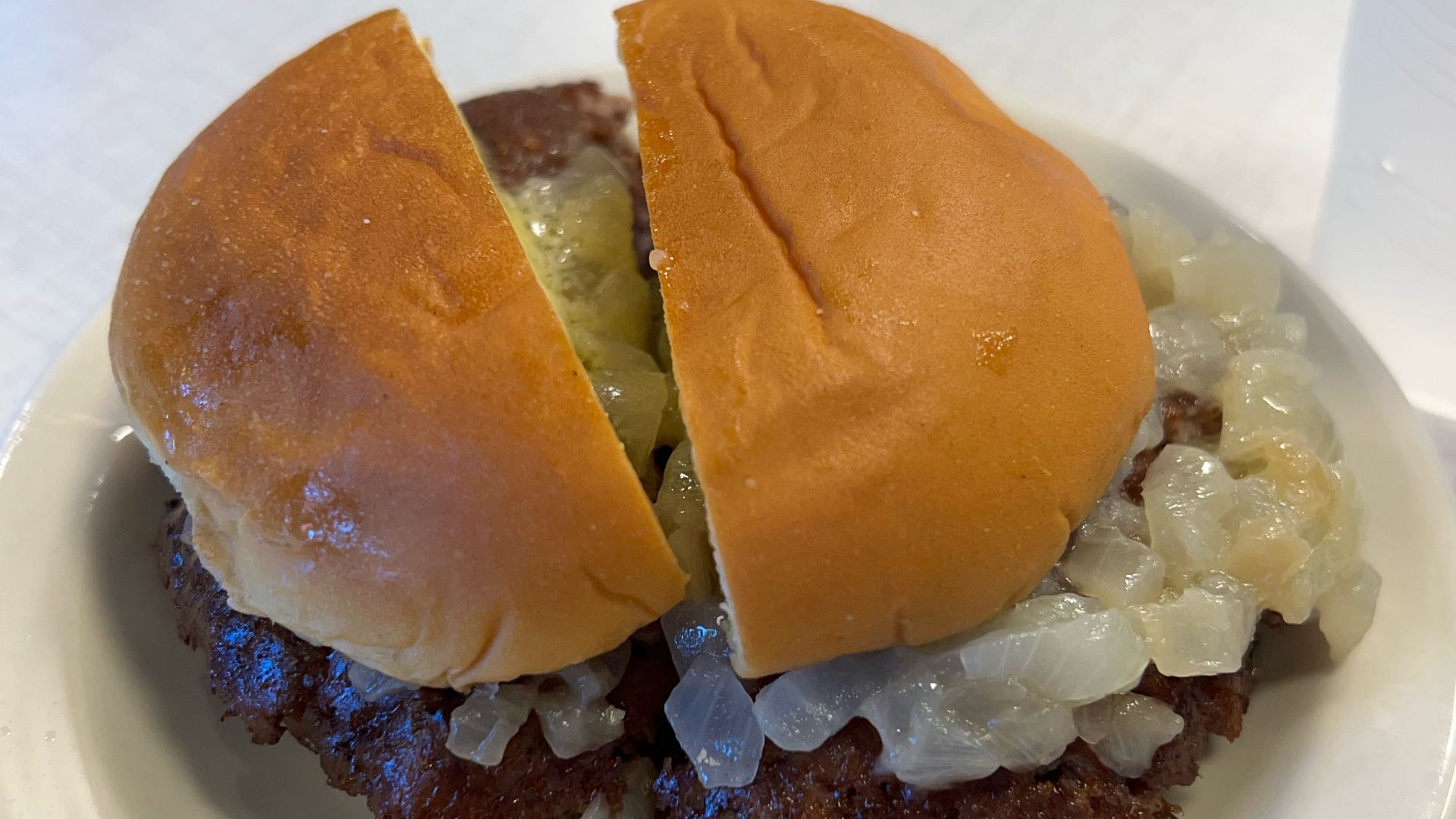 Double butter burger with stewed onions on a small plate at Hamburger America in SoHo, Manhattan, New York