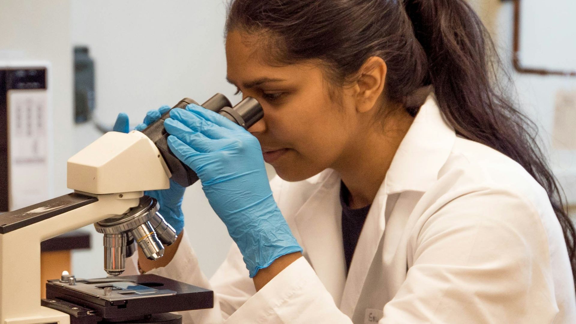 woman looking on microscope inside room
