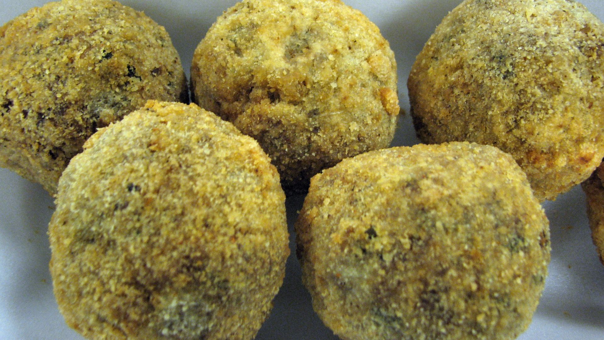 Photograph of Boudin sausage balls; a Cajun variation on Boudin blanc. The sausage is made of pork and rice, then instead of being packed into casings, its rolled into a ball, battered, and deep fried.