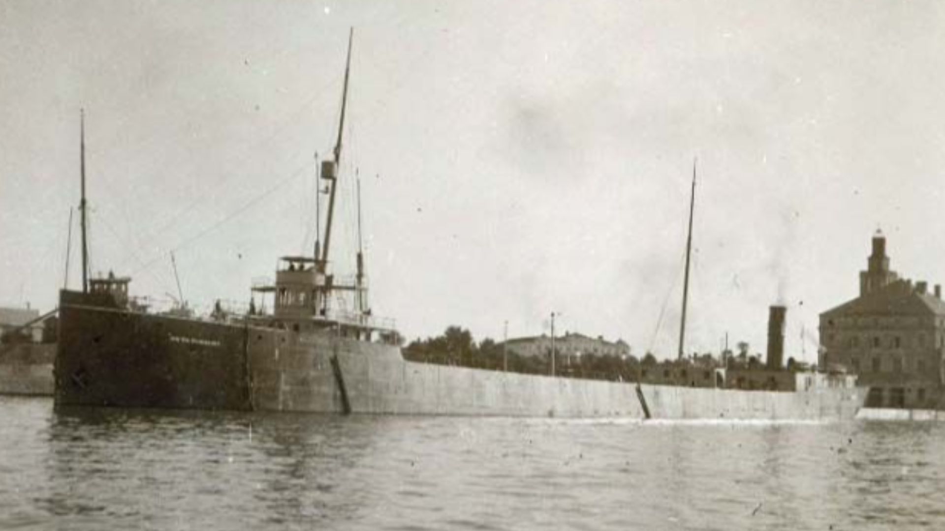 From the Antone S. Zeitler photograph album, cargo ship, the Sr. Wm. Fairbairn, is viewed docked at Mackinac Island around 1900. Commercial buildings are visible on the shoreline. Terms associated with the photograph are: Sir Wm. Fairbairn (Ship) | Mackin