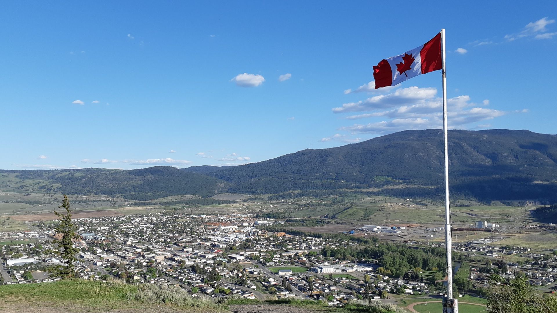 Merritt is a city in British Columbia, Canada. This photo is taken from a privately-owned, publicly-accessible lookout point, and shows the city in the Nicola valley on a summer's day, with a large Canadian flag flying