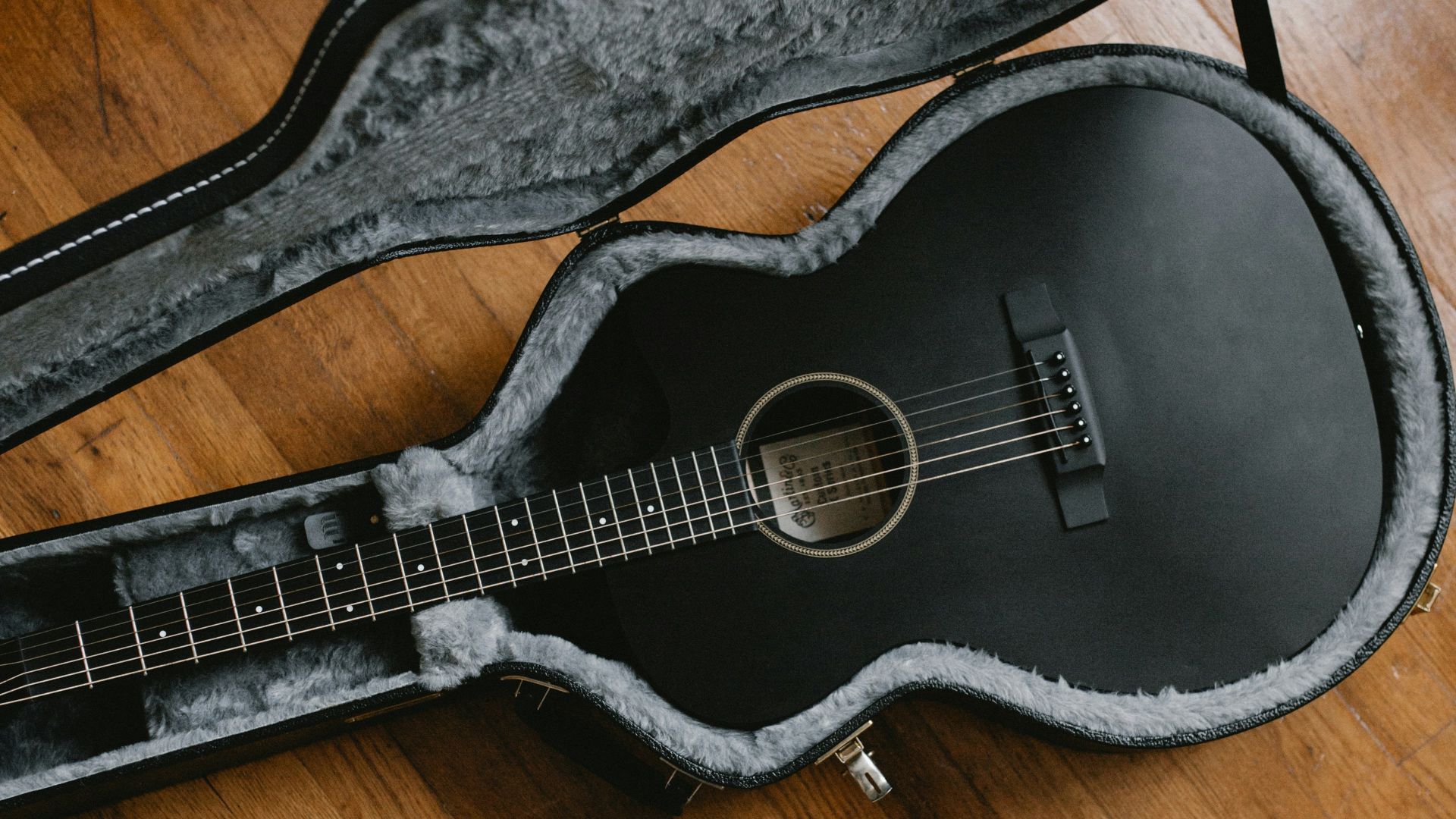 person taking picture of black classic guitar inside black and gray guitar case
