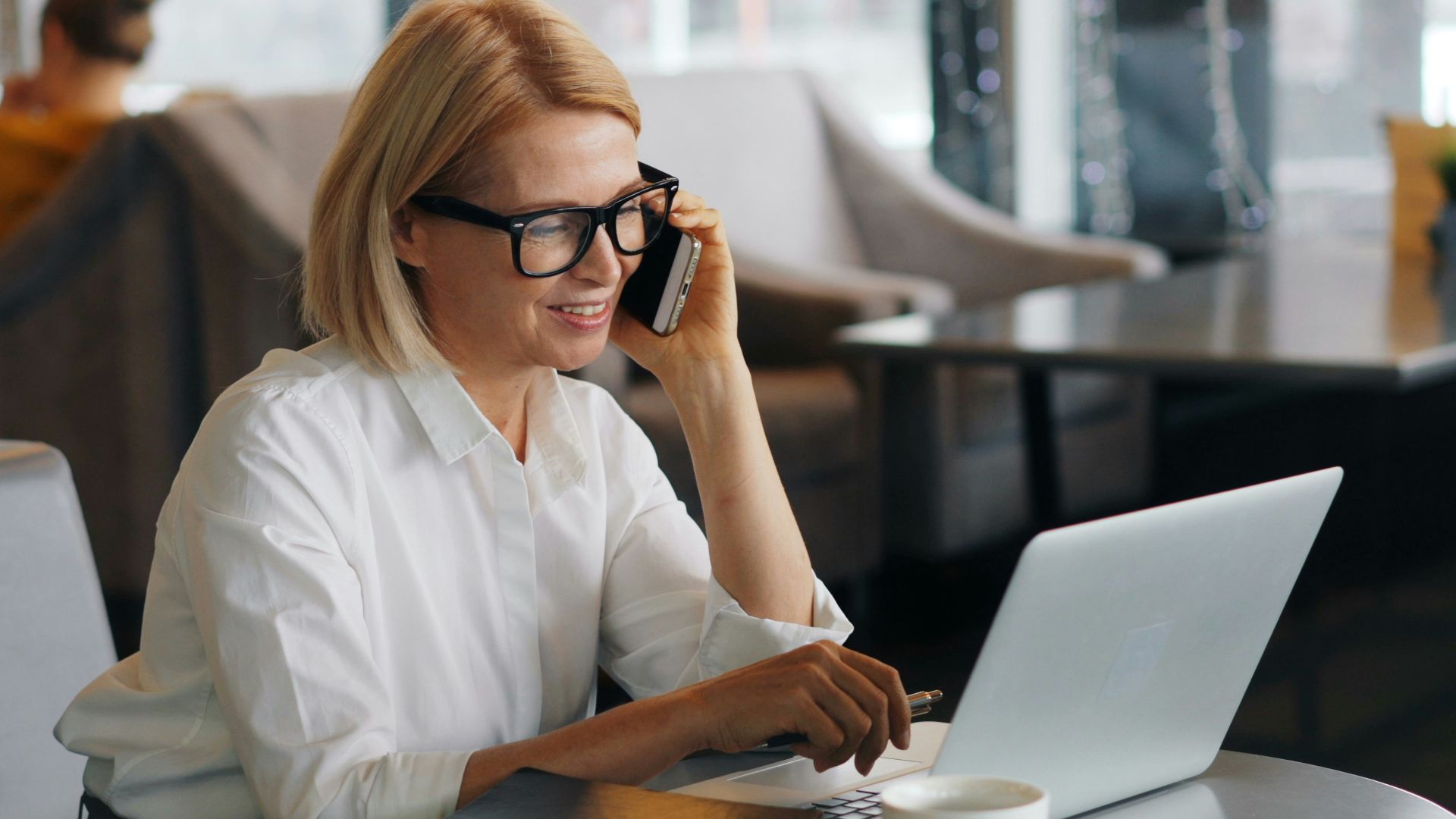a woman talking on a cell phone while using a laptop