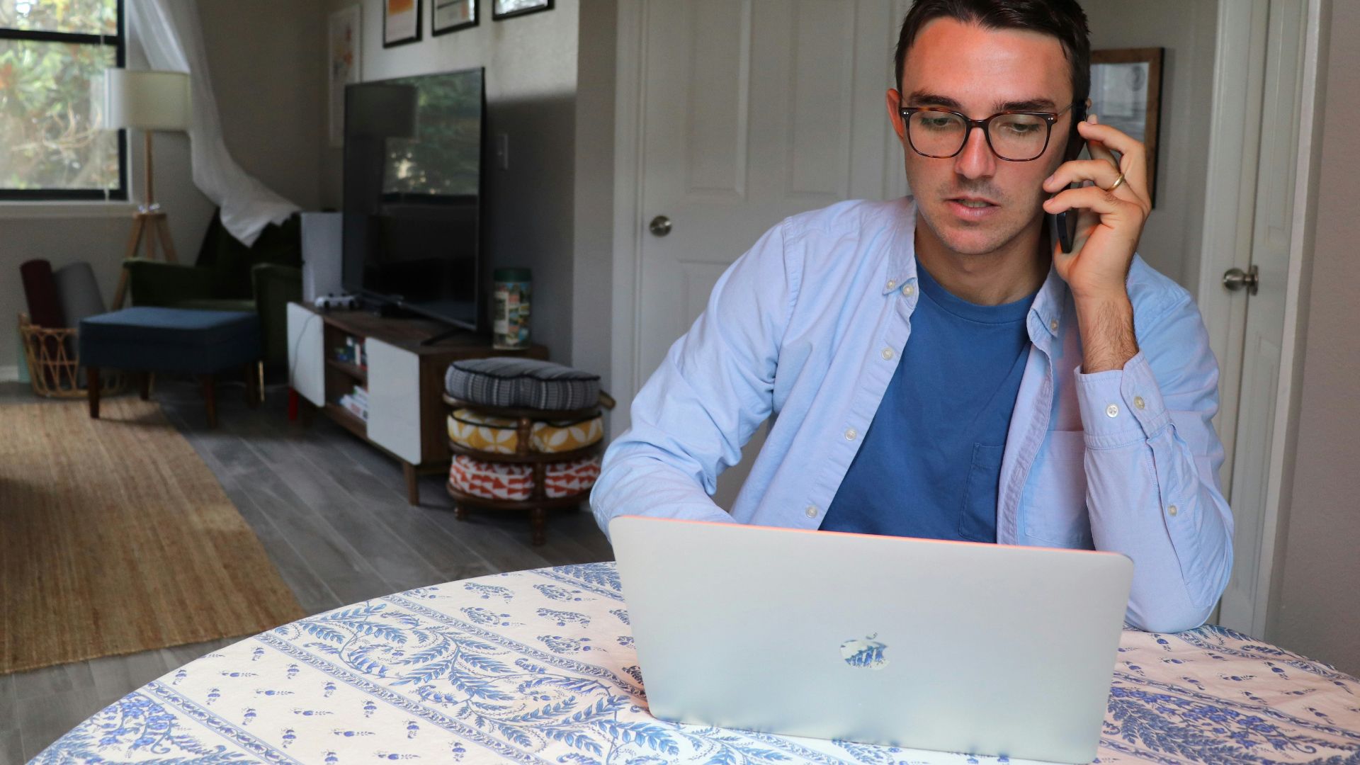 man in white dress shirt wearing eyeglasses sitting by the table using macbook