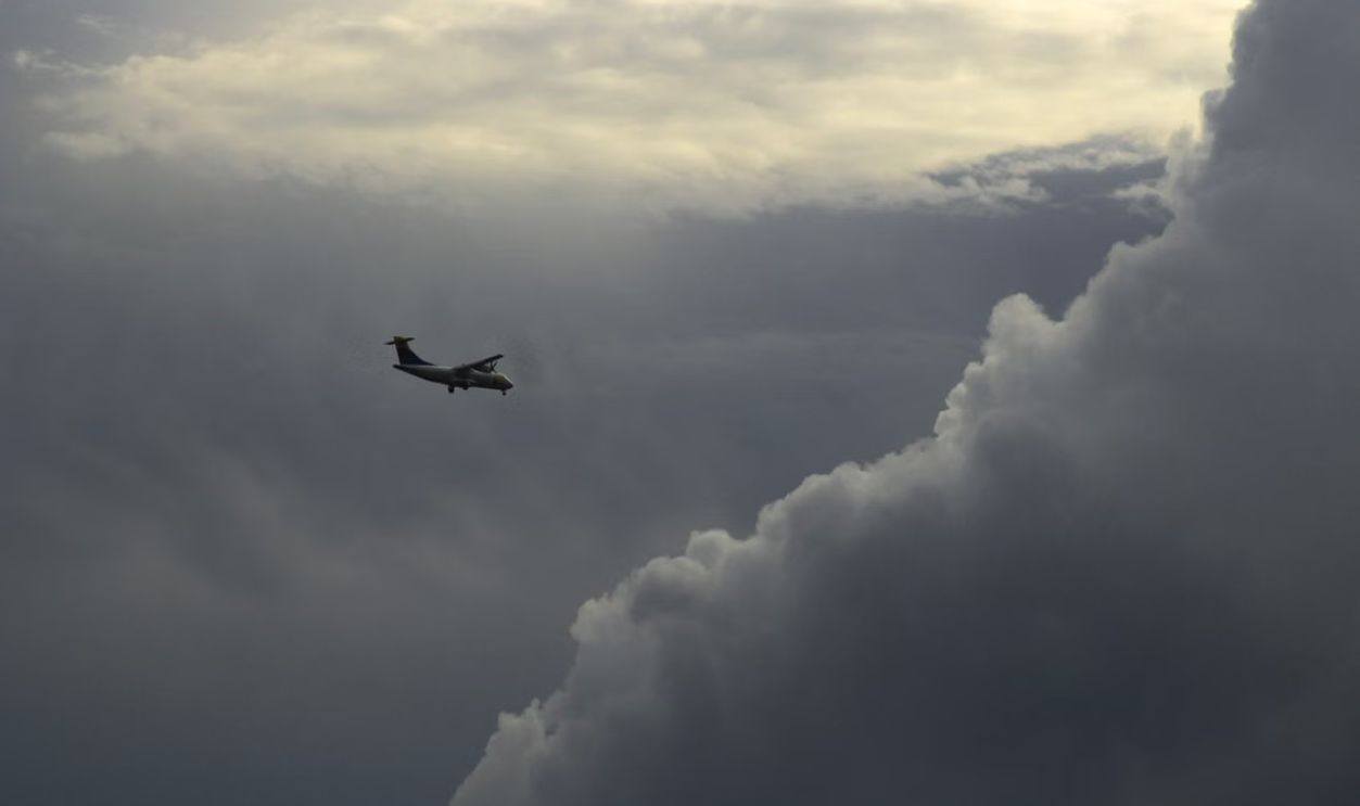 An airplane navigates a turbulent sky, surrounded by dramatic cloud formations during flight