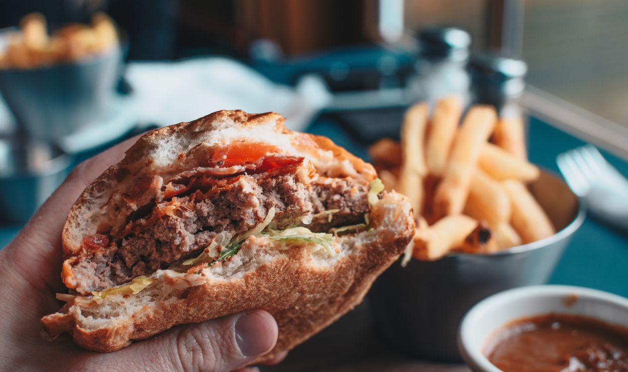 POV of man eating hamburger / hand holding half eaten hamburger