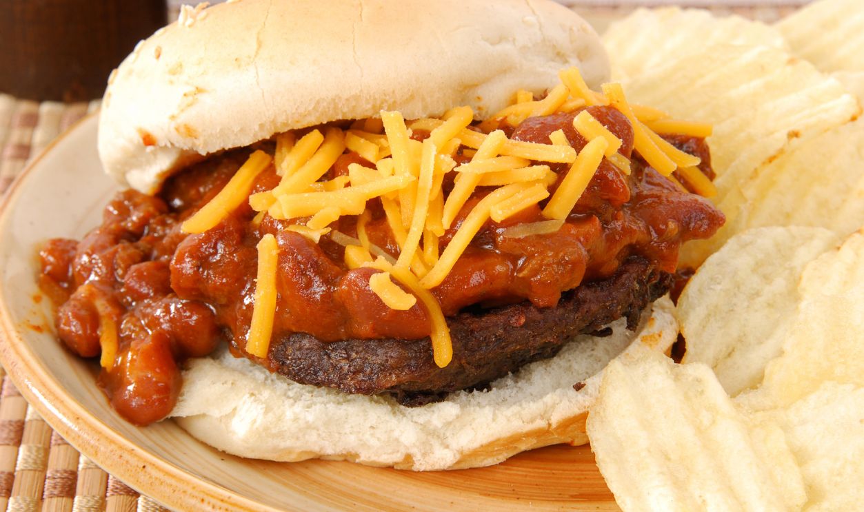 A hamburger smothered in chili and cheese