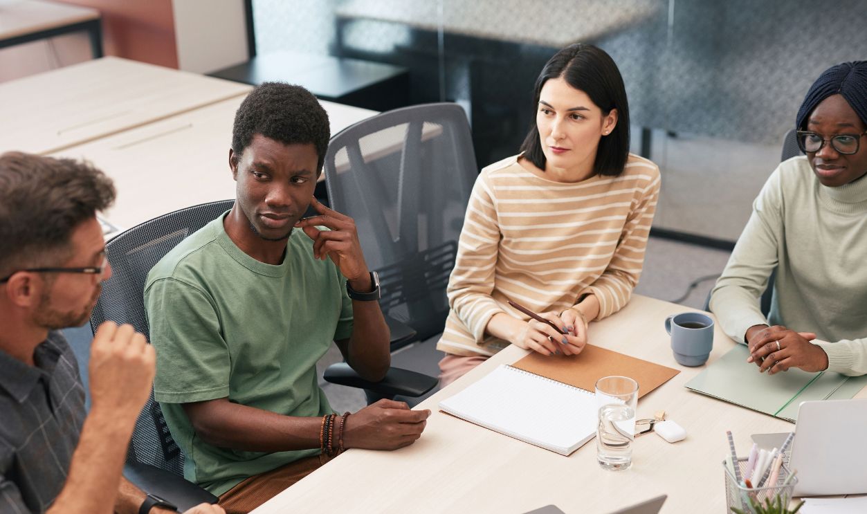 A diverse group of colleagues actively participating in a team meeting inside a modern office.