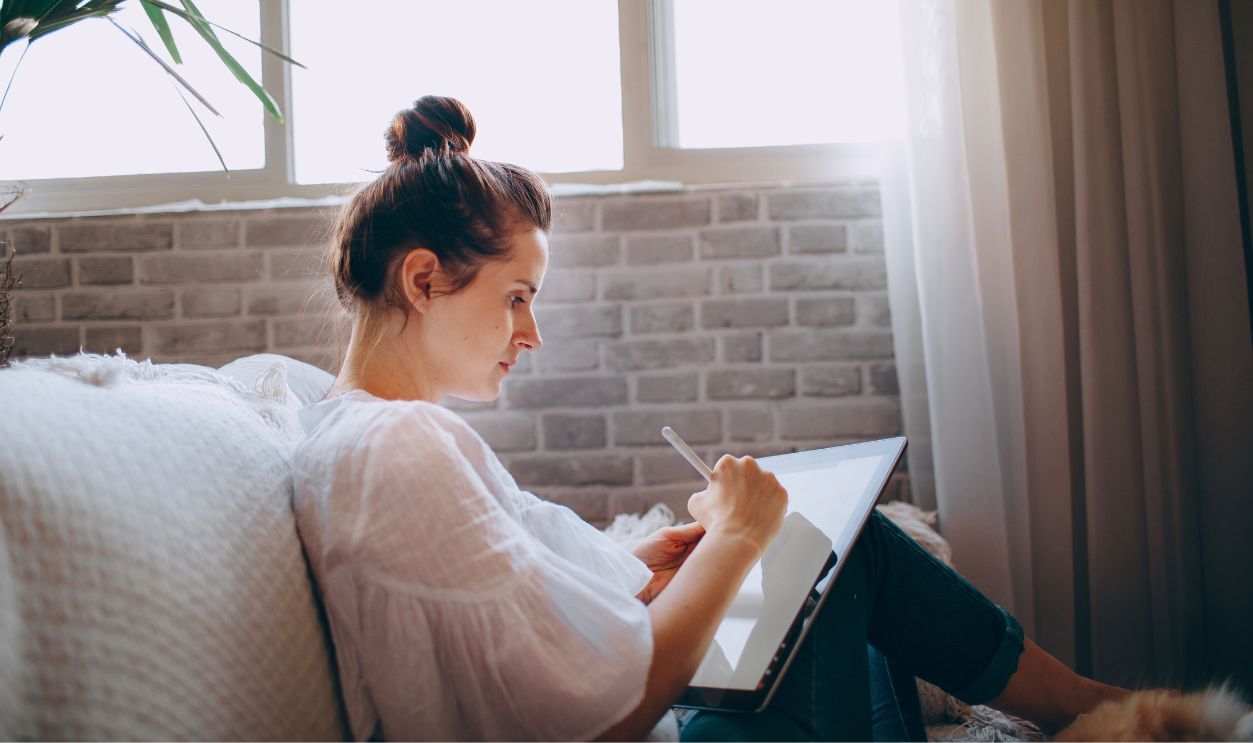 Woman sitting comfortably on a sofa using a digital tablet