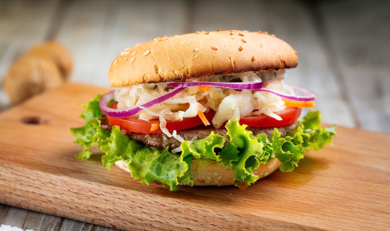 Closeup on hamburger with sauerkraut and lettuce on the wooden board