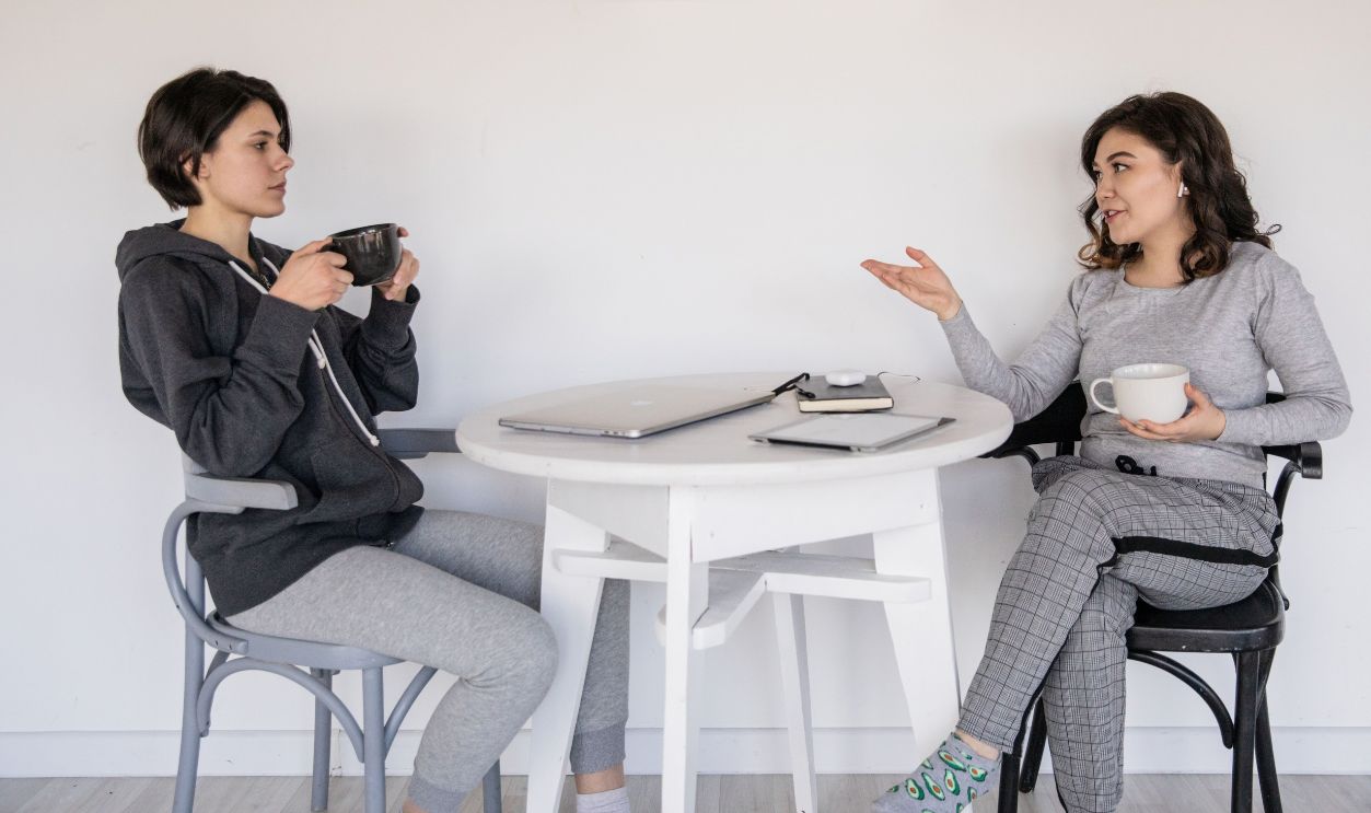 Two women enjoying a casual conversation with coffee in a cozy indoor setting