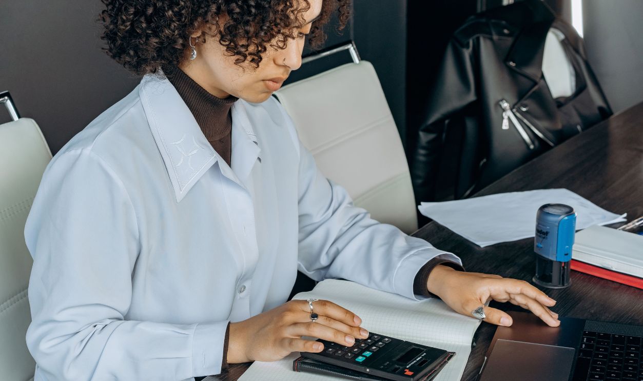 Young woman in office using a calculator
