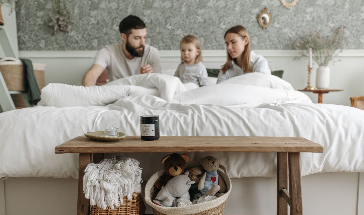 A family with a child enjoys a calm morning in a cozy and stylish bedroom setting.