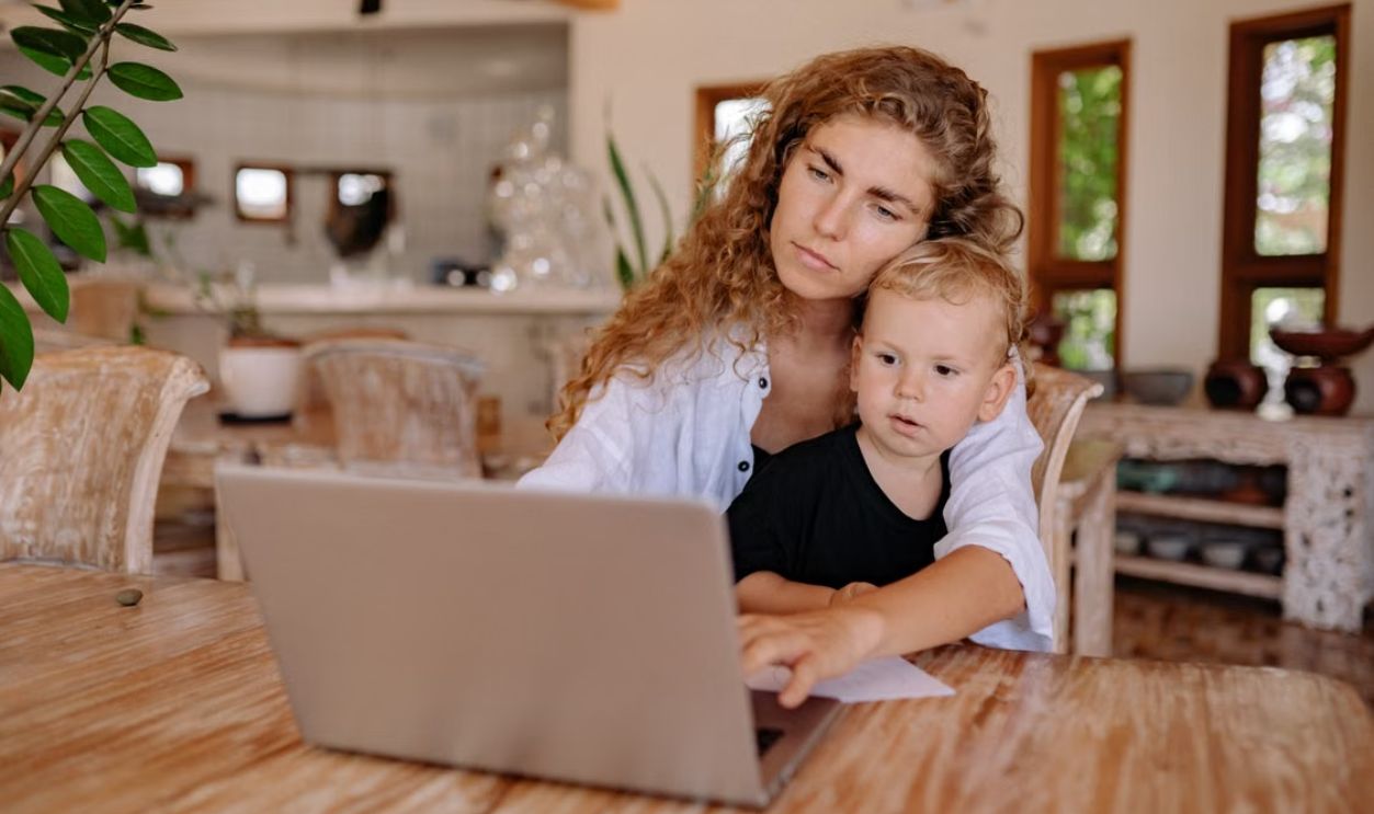Mother and child using a laptop at home, working and bonding in a cozy environment.