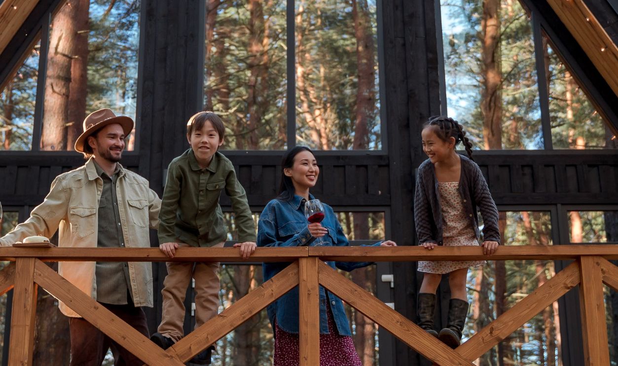 A family enjoys their vacation at a modern A-frame cabin nestled in a peaceful forest setting.