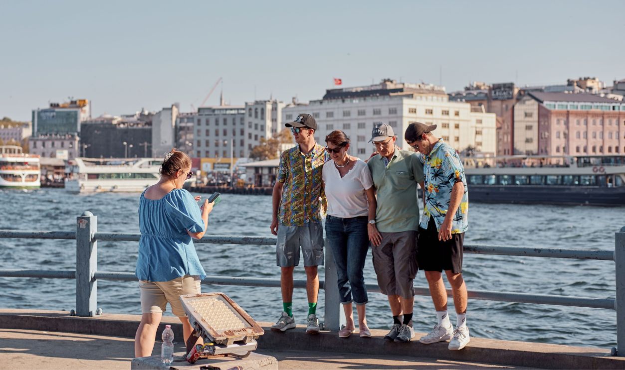 A family poses for a photo by the Bosphorus in İstanbul, capturing a memorable moment.