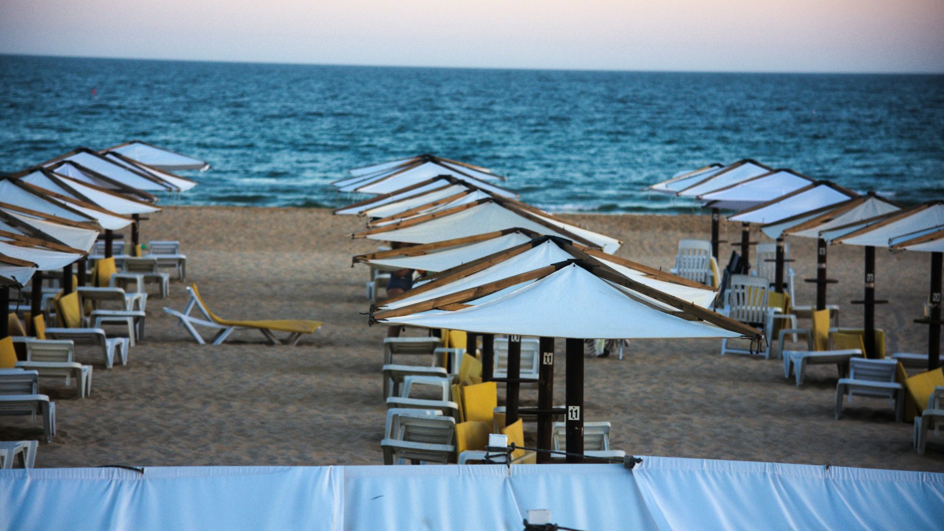 Beach with white umbrellas and lounge chairs by the ocean