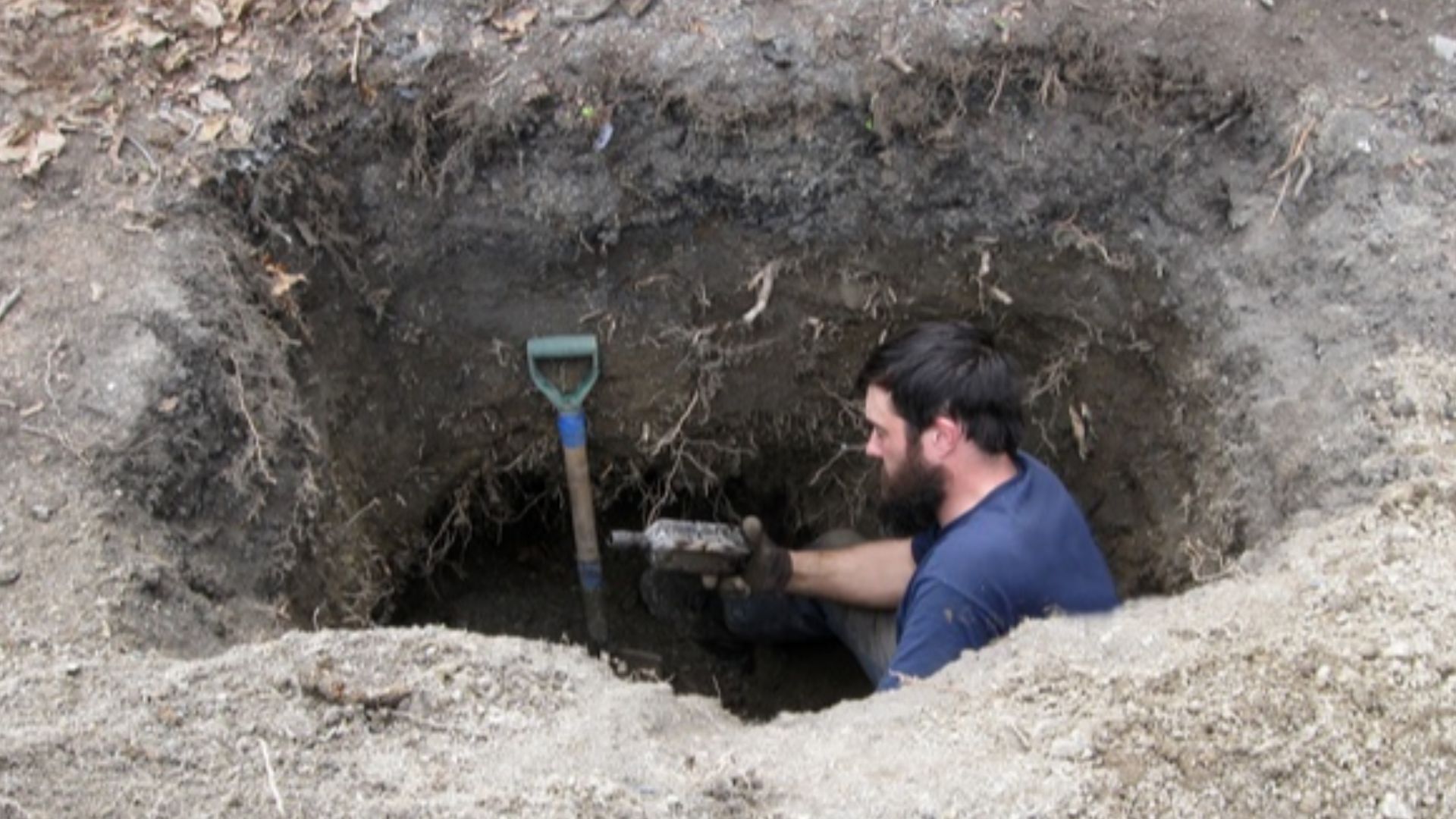 Excavating antique bottles and other items in a wood-lined privy (1860s-1920s).