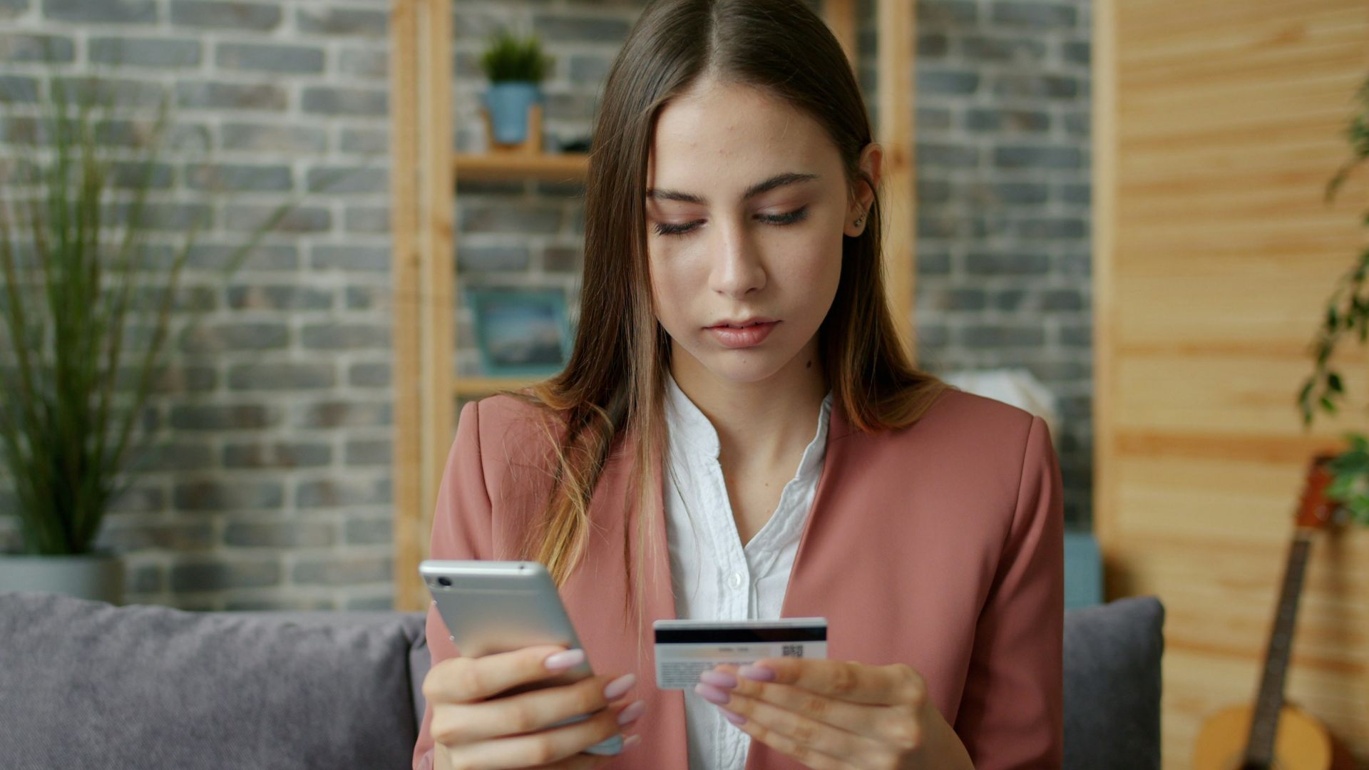 Young woman holding credit card and smartphone