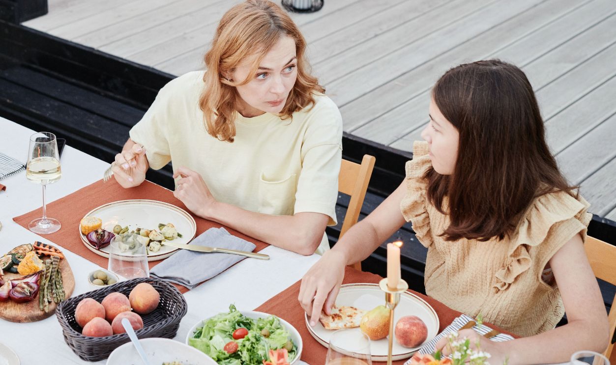 Family enjoying a meal outside with fresh food, wine, and candles creating a cozy atmosphere.