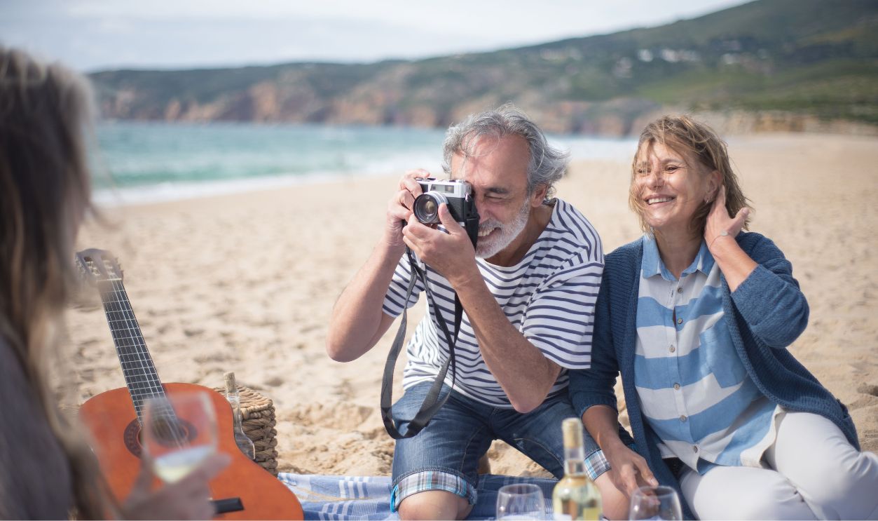 Happy senior couple having a picnic on a Portuguese beach, capturing memories.