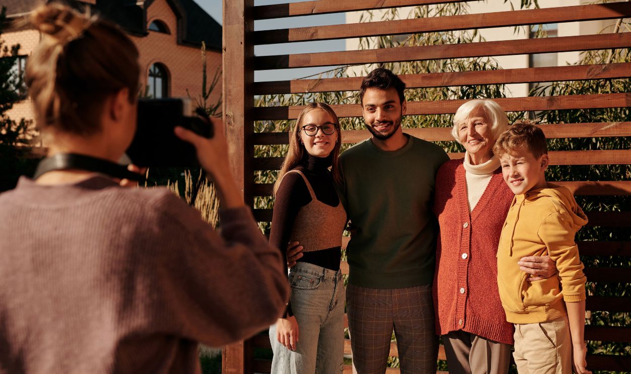 A cheerful family posing outdoors for a photograph on a sunny day, capturing generations together in harmony.