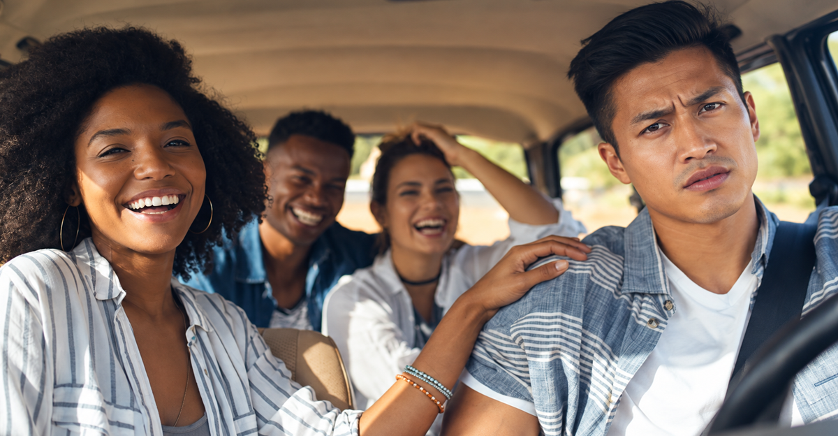 Frustrated driver sits beside three laughing passengers in car