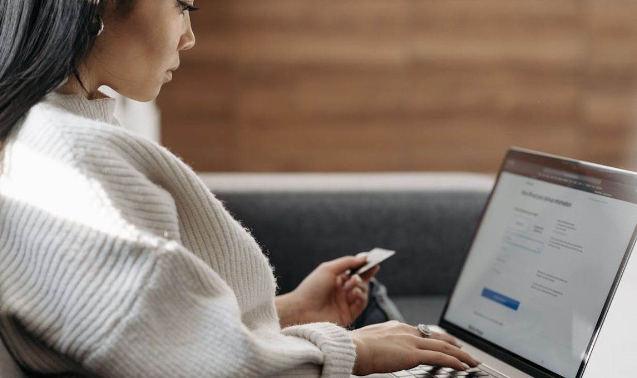 Woman in White Sweater Entering Card Details into Laptop