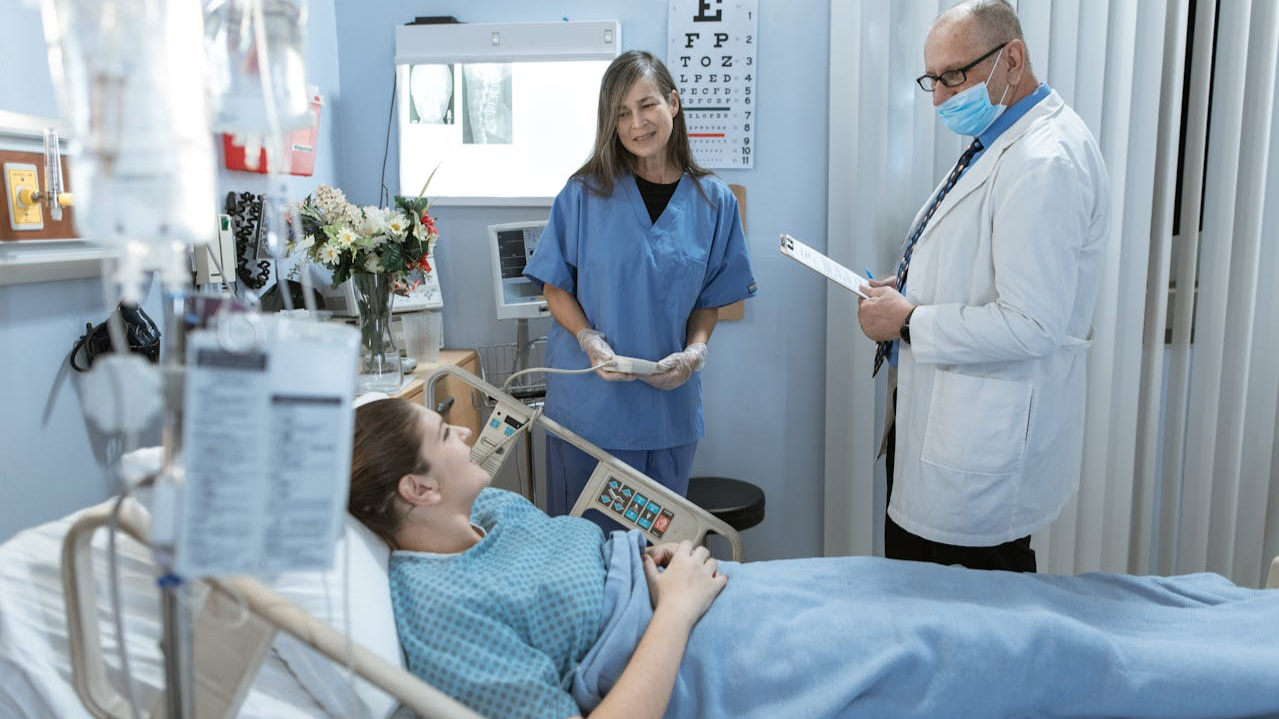 A Doctor and a Nurse Attending a Female Patient in Bed
