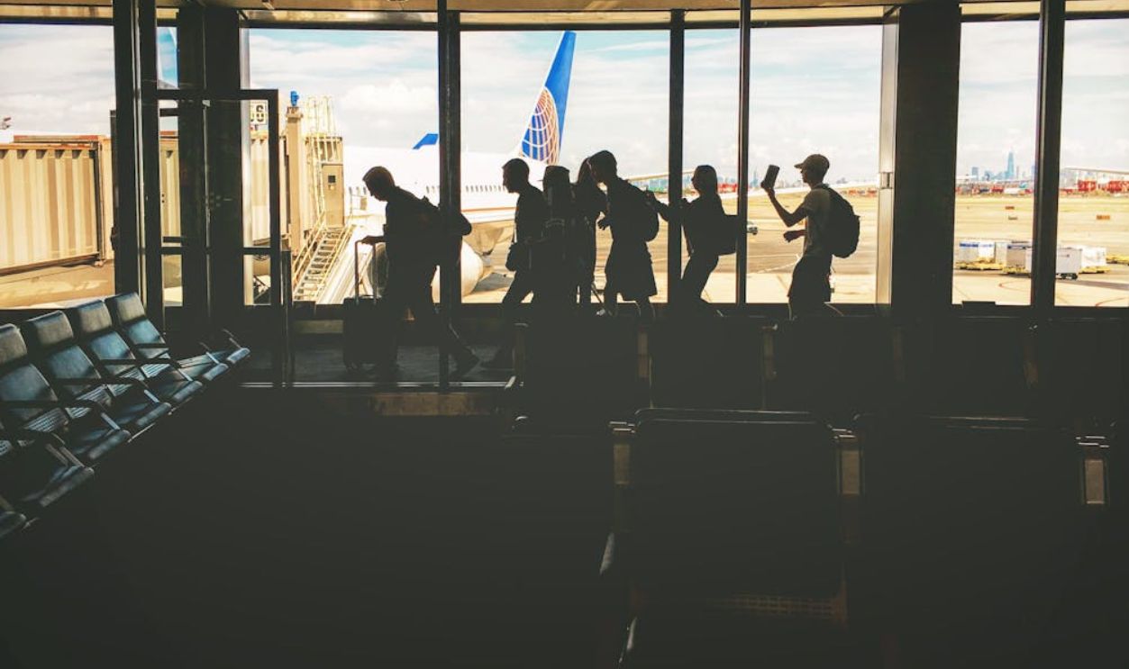 Group of People Walking Near Clear Glass Window With a View of White Airplane Parked during Daytime