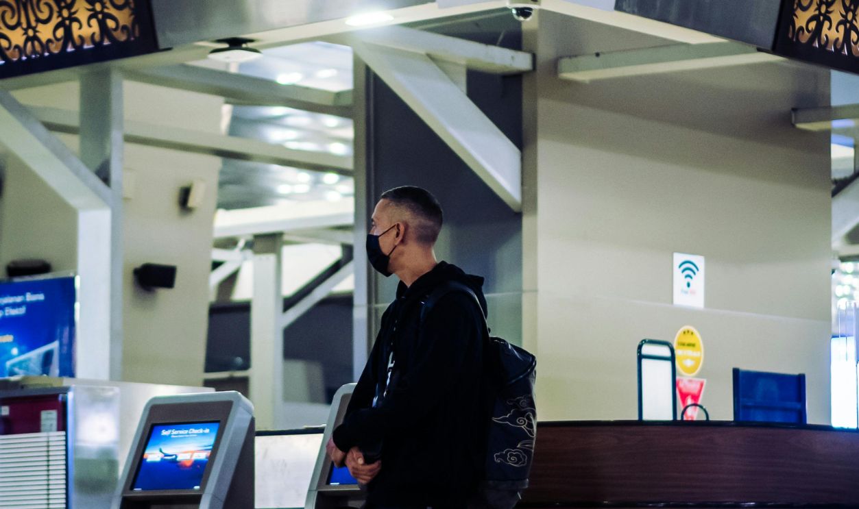 Man in Black Jacket and Black Pants Standing Beside Counter