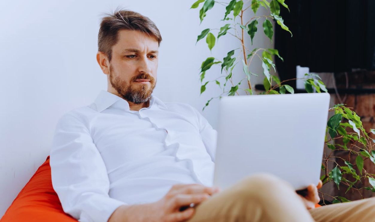 A Man in White Long Sleeves Using a Laptop