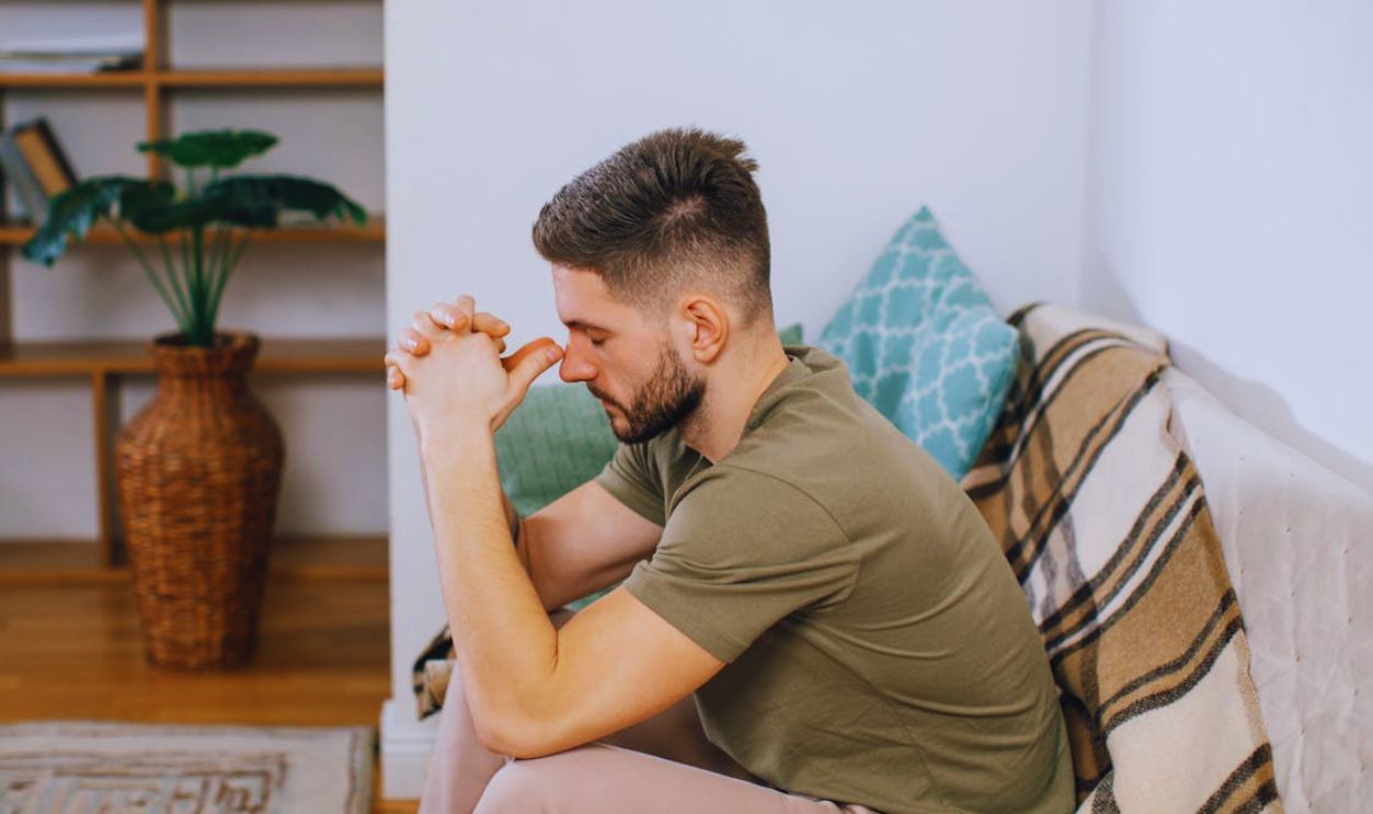 A Man Sitting on a Sofa while His Hands are Together