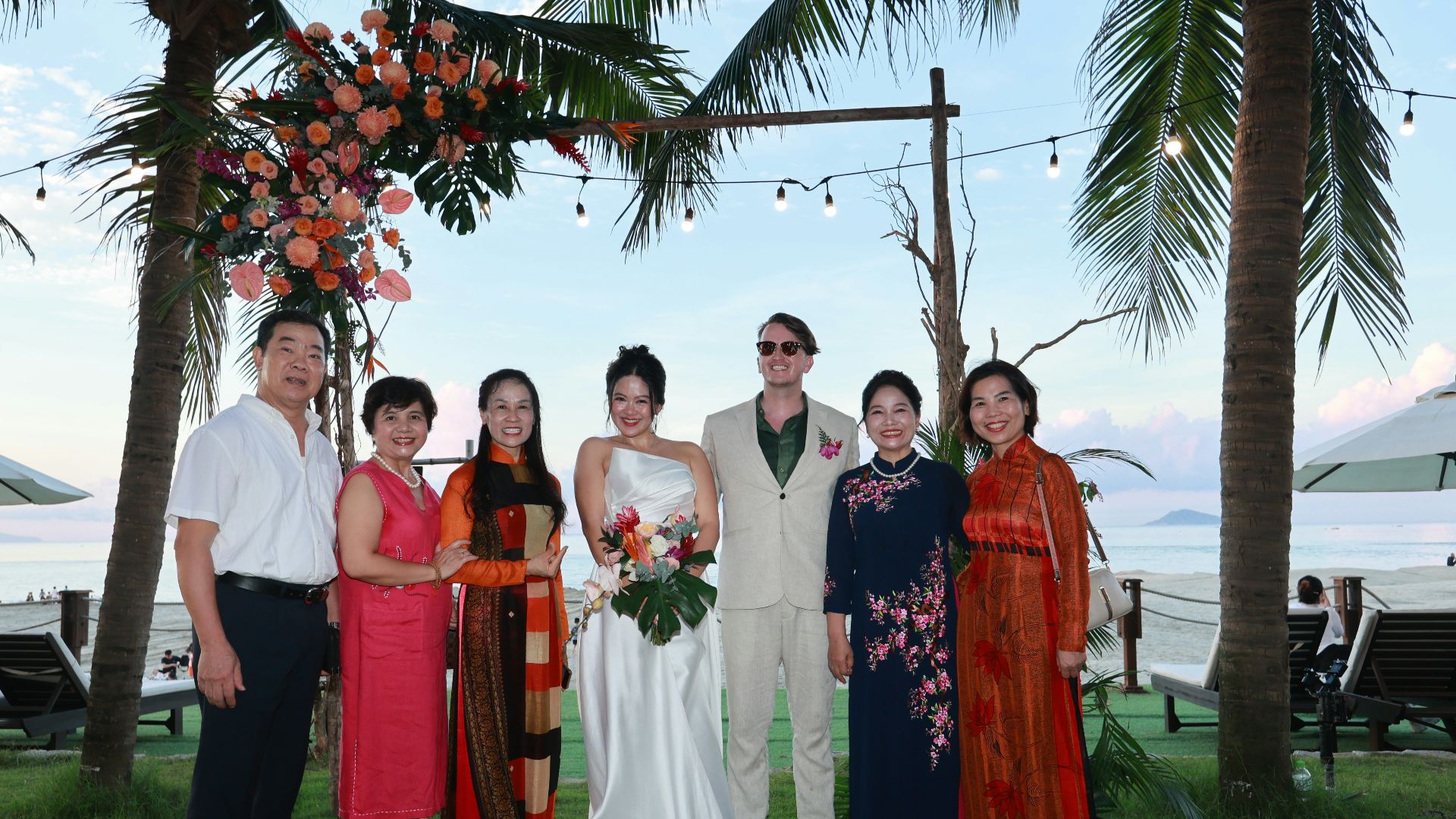 Wedding party posing on beach under palm trees