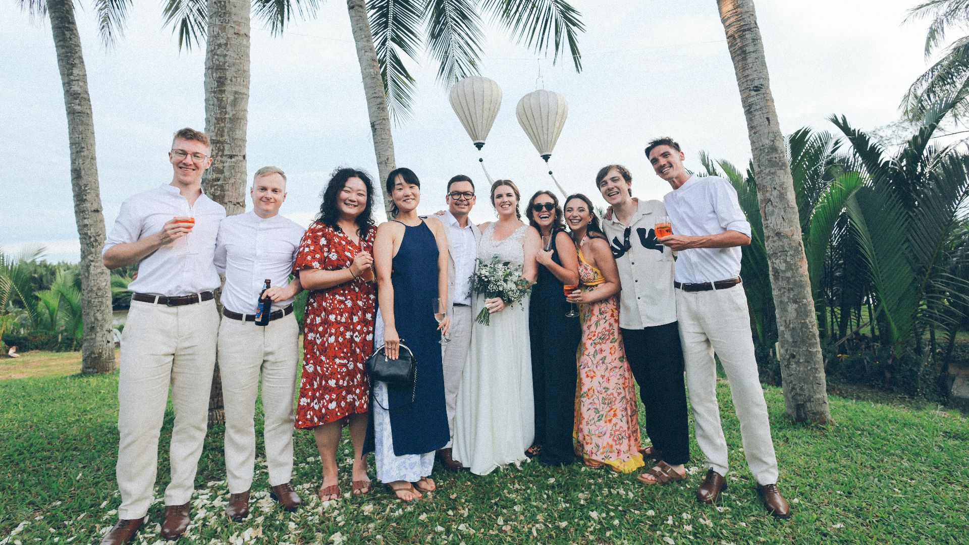 Wedding party posing under palm trees with balloons.
