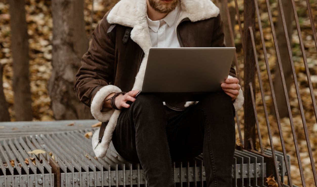 Woman in Brown Coat Sitting on Black Metal Bench