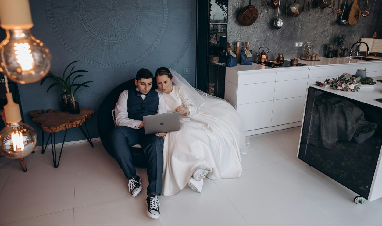 Bride and Groom Sitting While Looking at the Laptop