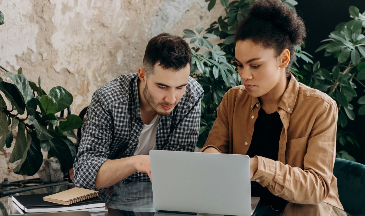 Man and Woman Sitting on Chair While Using Laptop