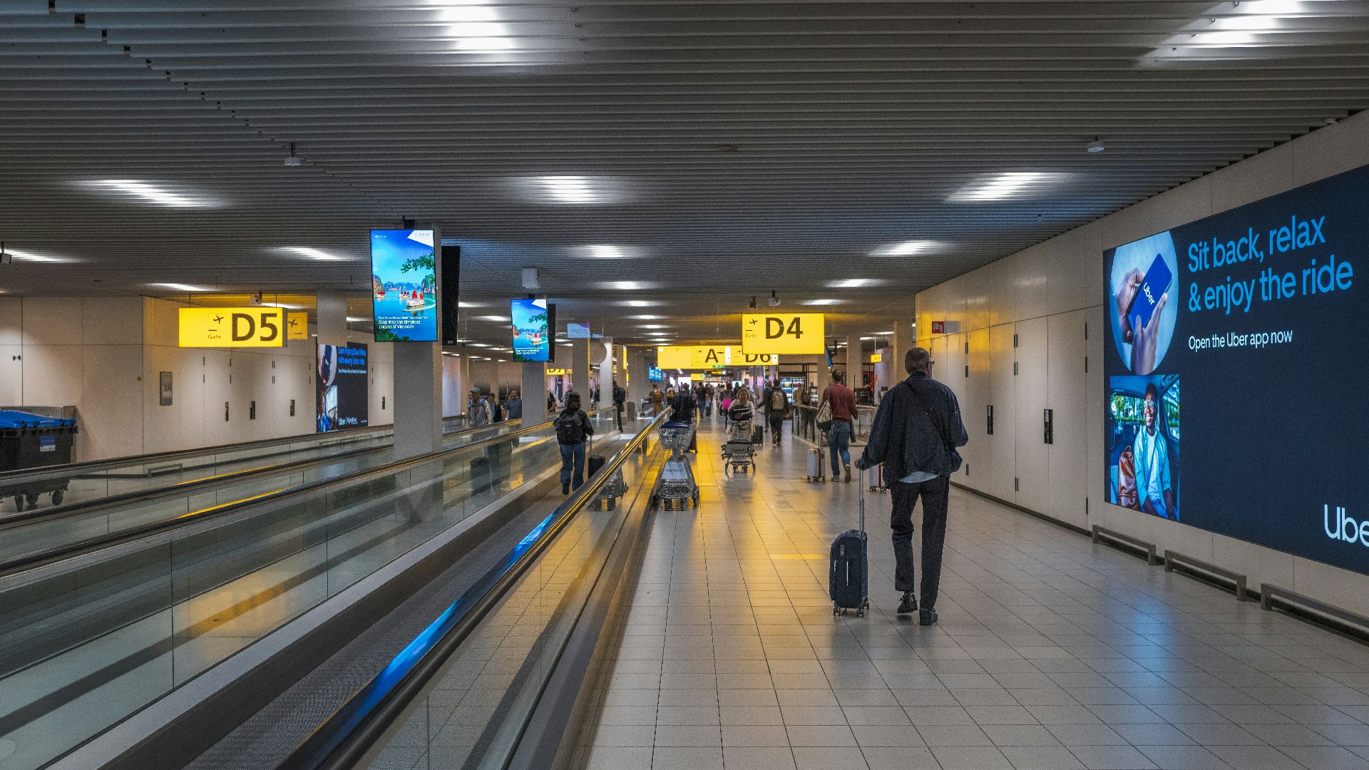 People walking in a modern airport terminal with moving walkways.