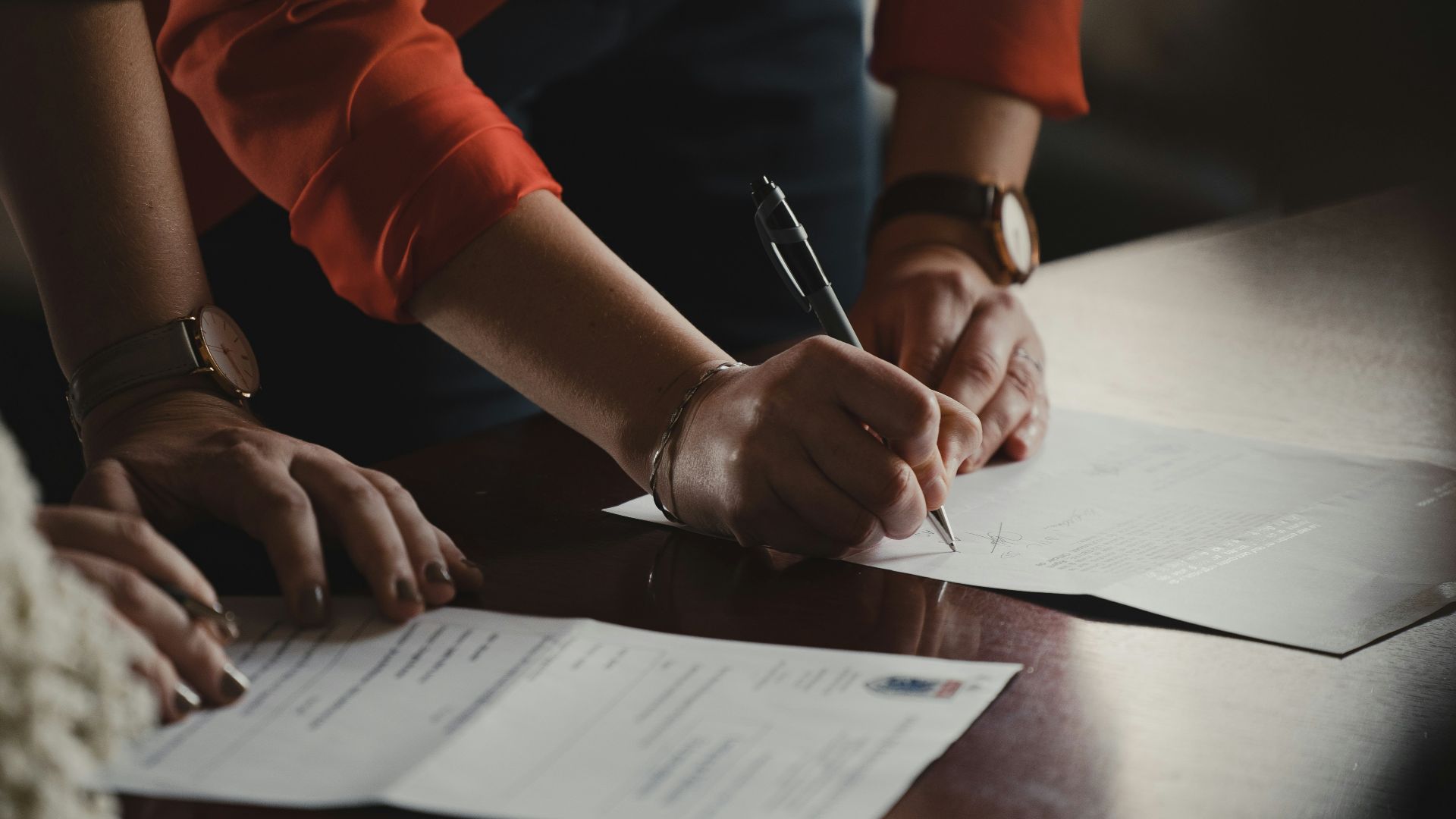 person in orange long sleeve shirt writing on white paper