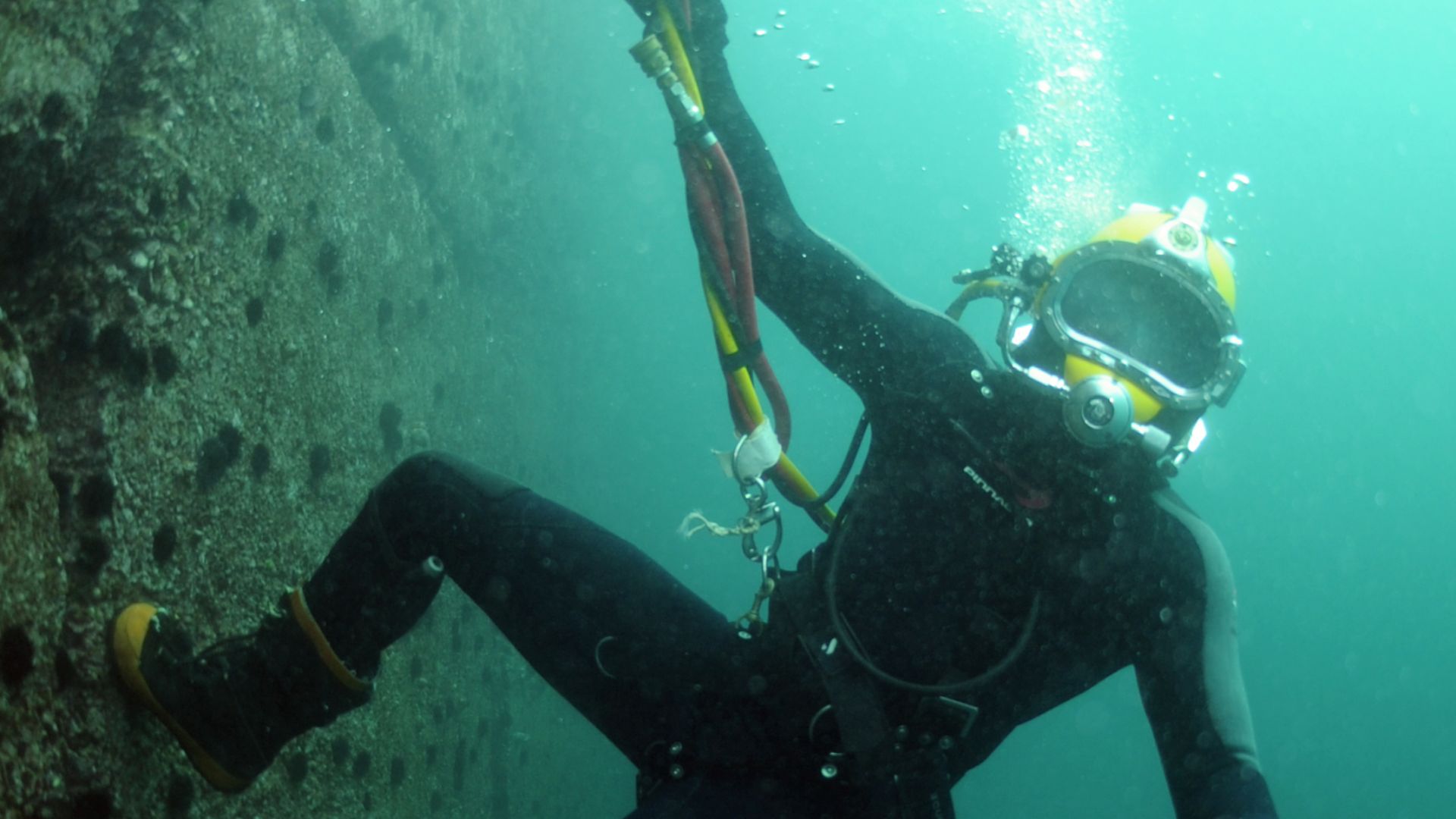 File:US Navy 110629-N-XD935-163 Navy Diver 3rd Class Bryan Myers climbs to the surface along the pier wall after conducting diving operations.jpg